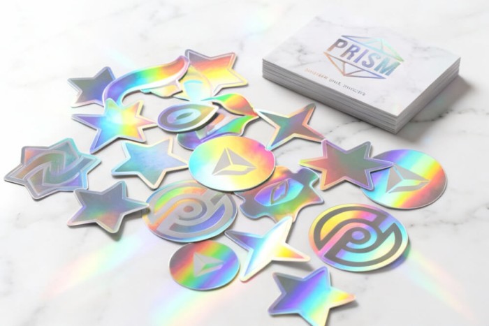 Guida agli adesivi olografici personalizzati che mostra effetti di diffrazione arcobaleno su pellicola di poliestere metallizzato