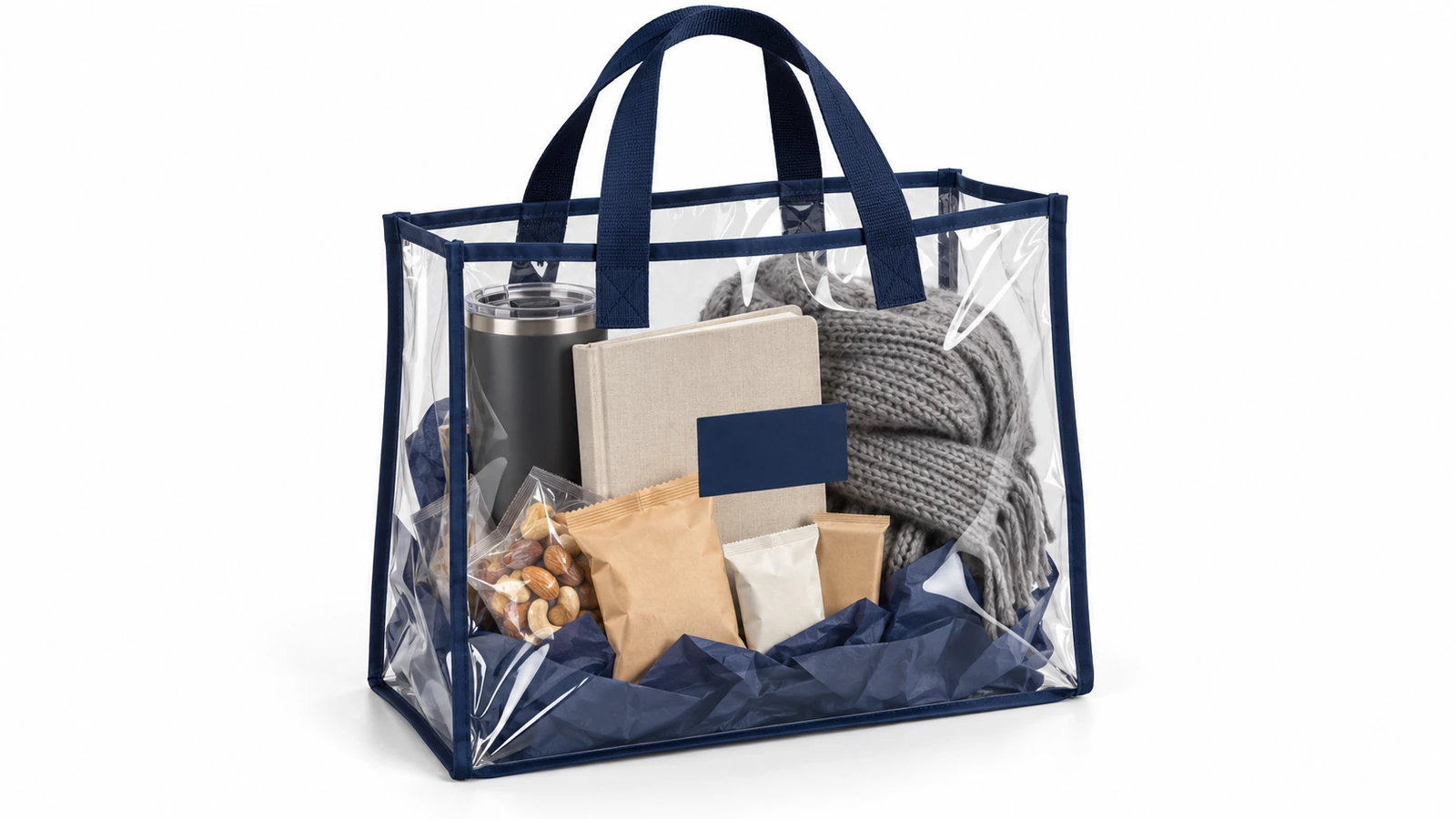 Shopper trasparente in PVC con bordatura blu navy che contiene un kit regalo aziendale curato con bicchiere termico, quaderno, snack e sciarpa piegata, tutti visibili attraverso la borsa