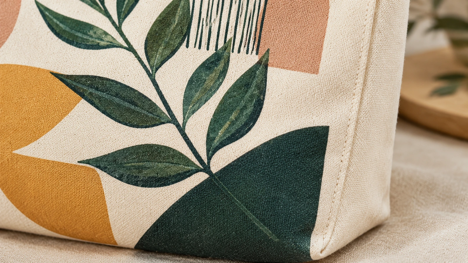 Primo piano di una tote bag in canvas stampata con grafica a foglie e soffietto laterale cucito
