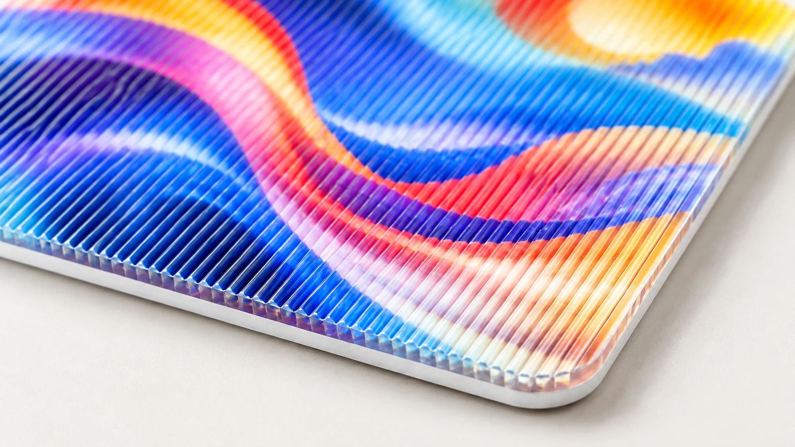 Primo piano di un campione lenticolare colorato che mostra rilievi paralleli e un angolo arrotondato