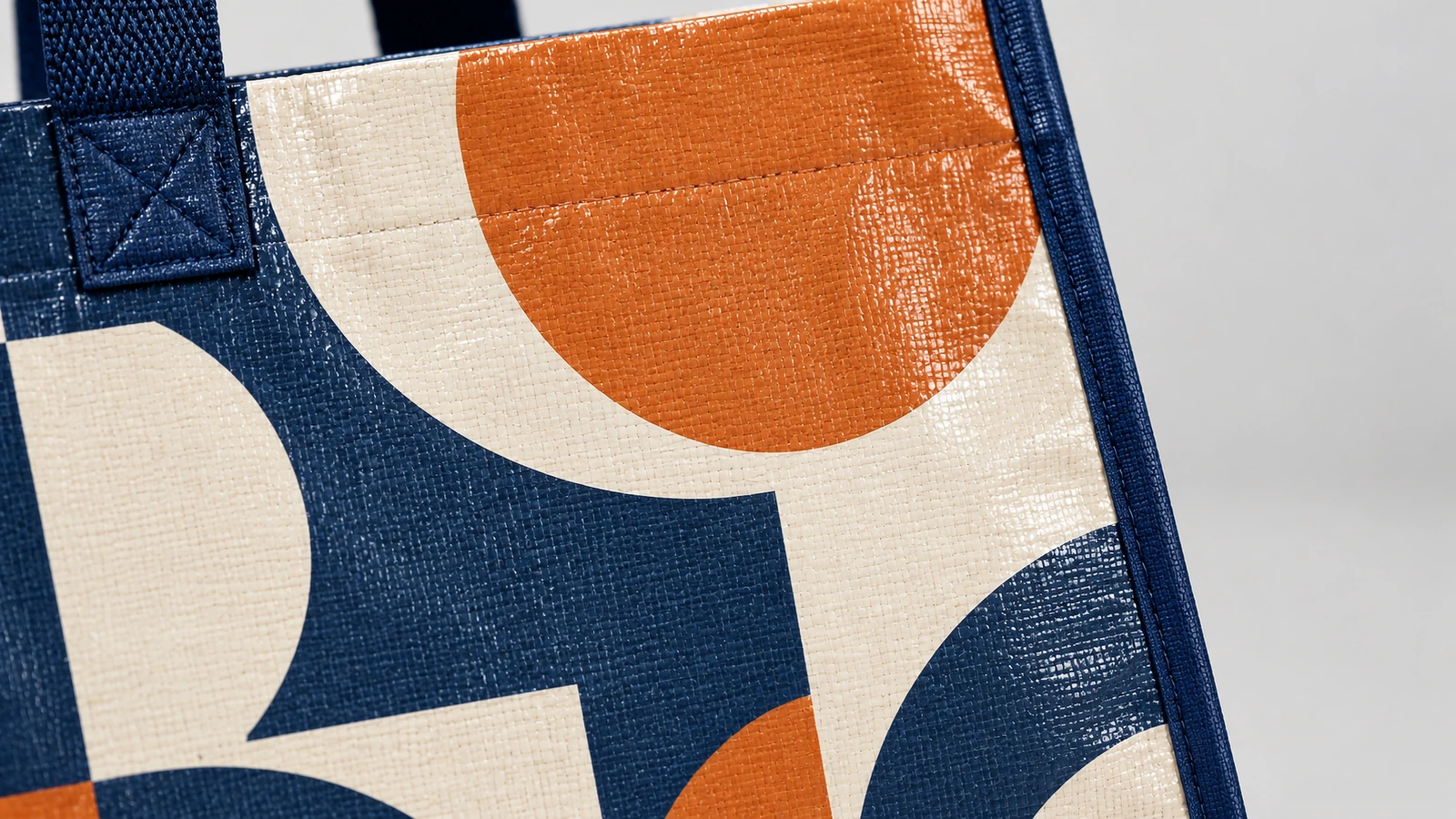 Primo piano del tessuto di borsa tessuto con stampa geometrica e del punto di unione rinforzato del manico blu navy