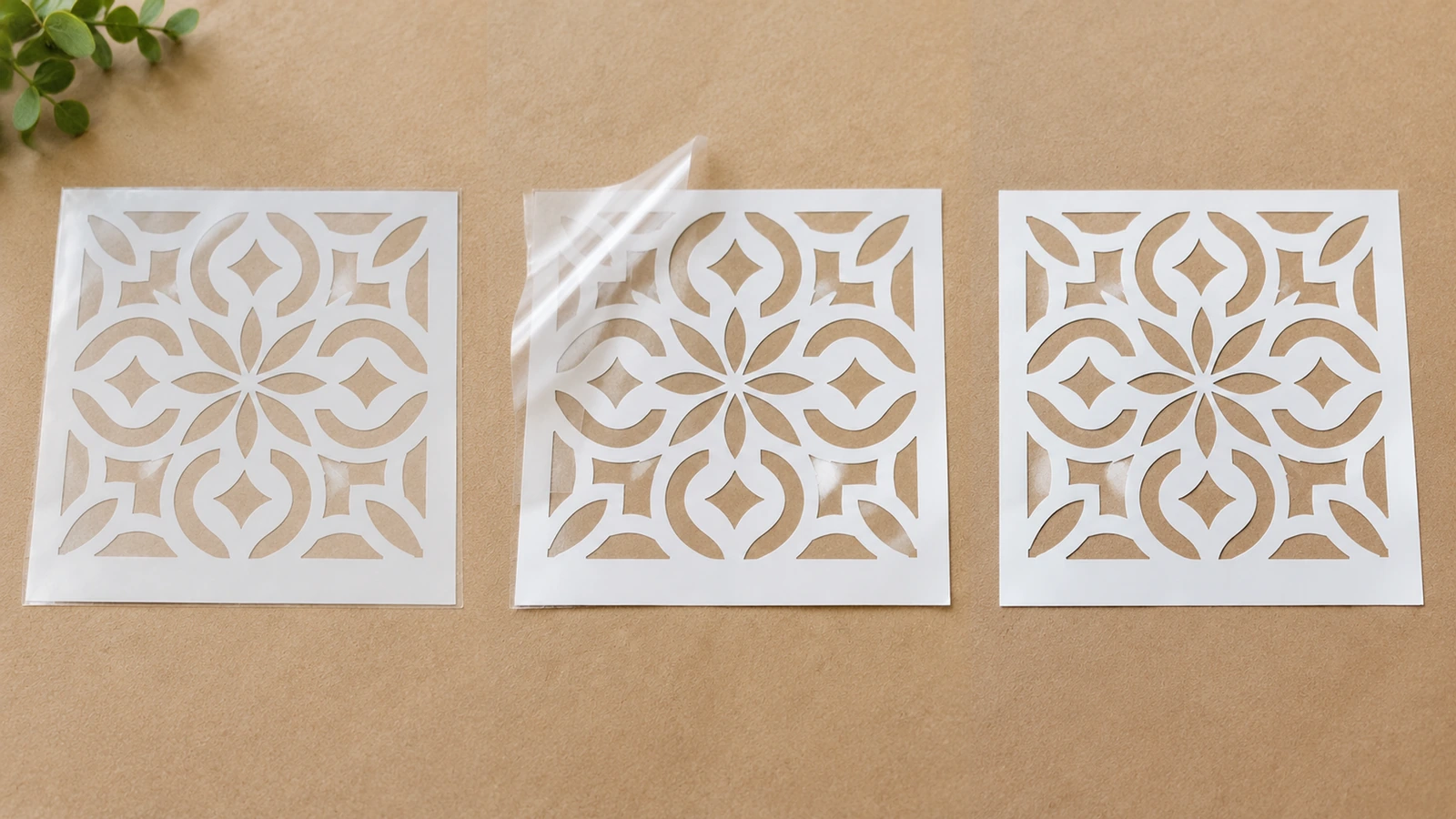 Tre fogli di stencil floreali bianchi disposti affiancati con gli strati trasparenti visibili
