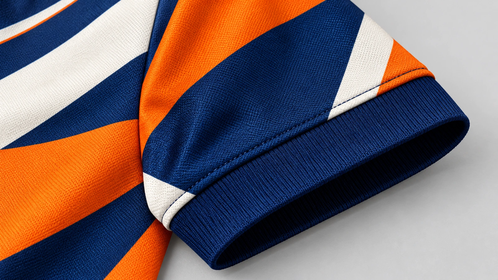 Primo piano di una manica a motivi arancio, blu navy e bianchi con polsino a costine blu navy